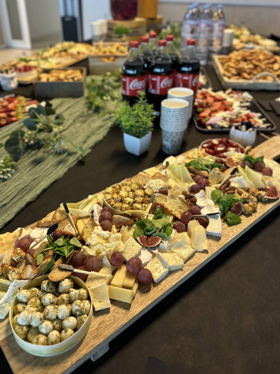 Buffet traiteur pour entreprise avec plateaux de fromages variés et boissons en jarres